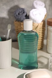 Photo of Bottle of mouthwash, toothbrush and soap on light table in bathroom