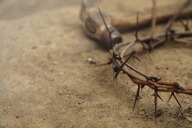 Photo of Crown of thorns and hammer on ground, closeup with space for text. Easter attributes