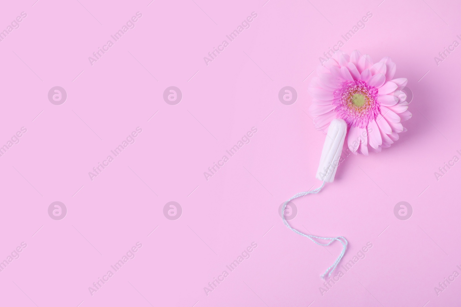 Photo of Flat lay composition with tampon and flower on pink background, space for text. Gynecology concept