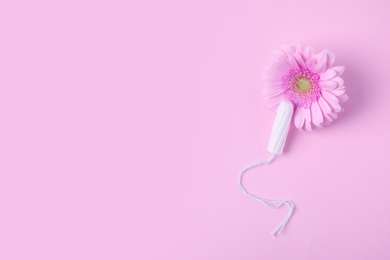 Photo of Flat lay composition with tampon and flower on pink background, space for text. Gynecology concept