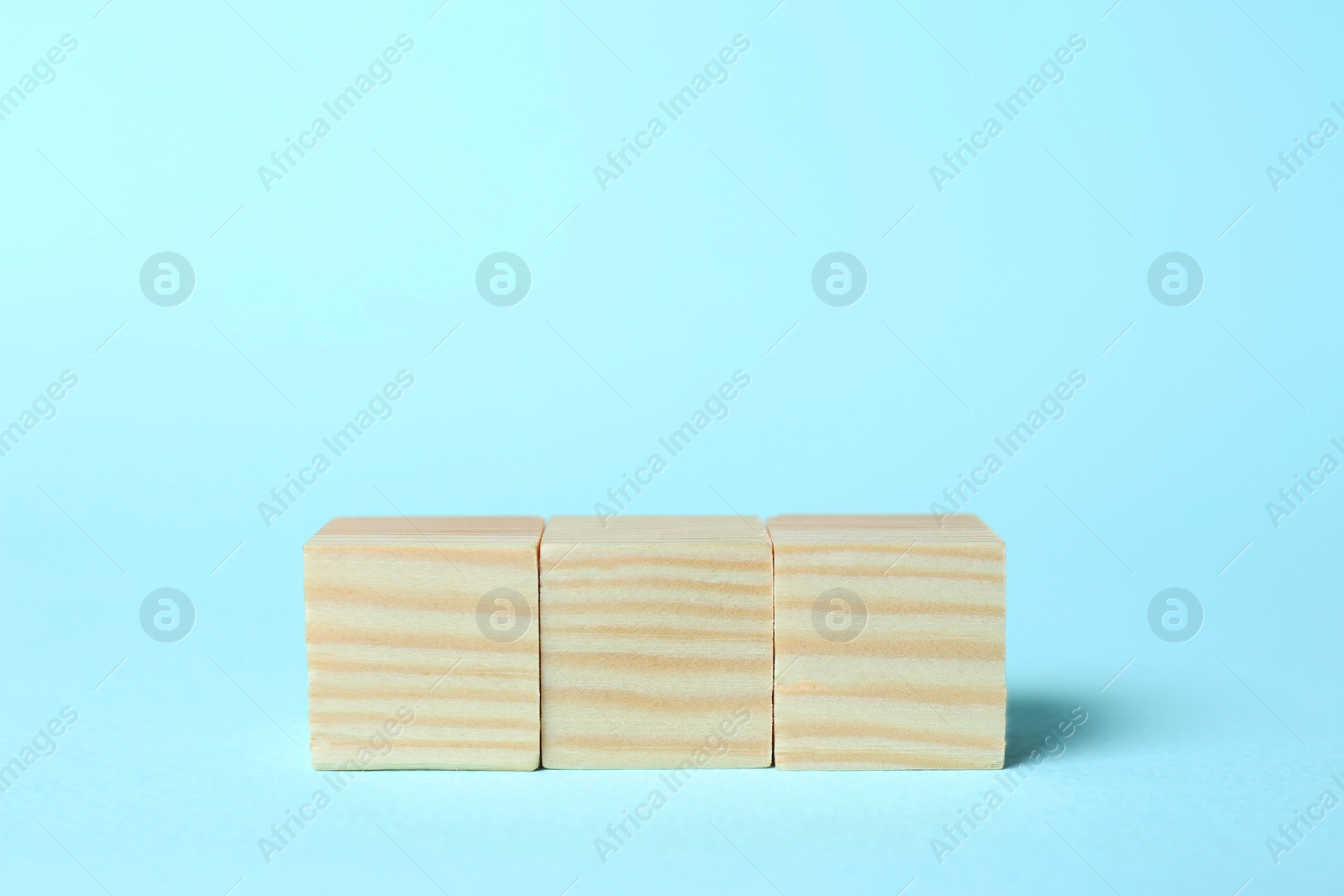 Photo of Wooden cubes on light blue background, space for text. Idea concept