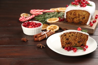 Traditional classic Christmas cake decorated with cranberries and rosemary on wooden table. Space for text