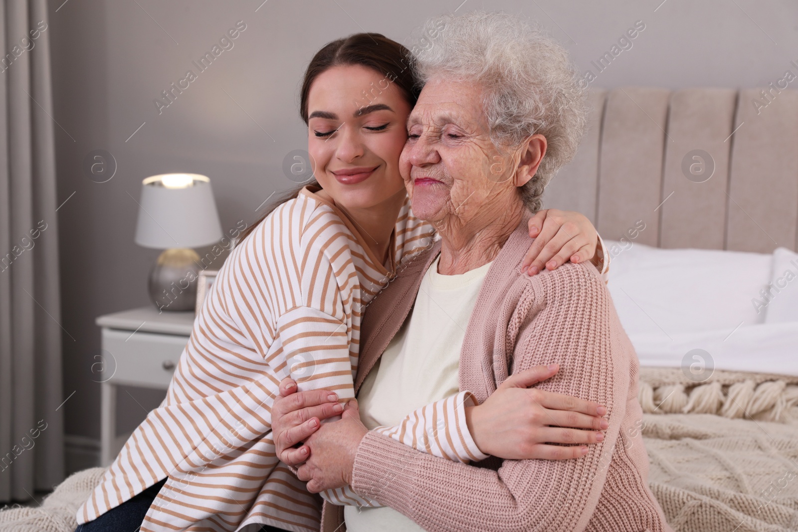 Photo of Young caregiver talking to senior woman in bedroom. Home health care service