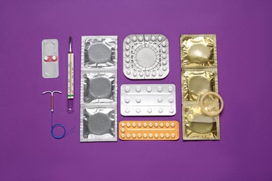 Contraceptive pills, condoms, intrauterine device and thermometer on purple background, flat lay. Different birth control methods