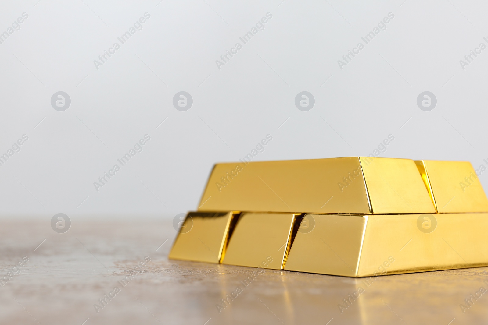 Photo of Stacked shiny gold bars on table. Space for text