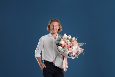 Photo of Young handsome man with beautiful flower bouquet on blue background