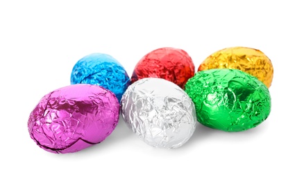 Many chocolate eggs wrapped in bright foil on white background