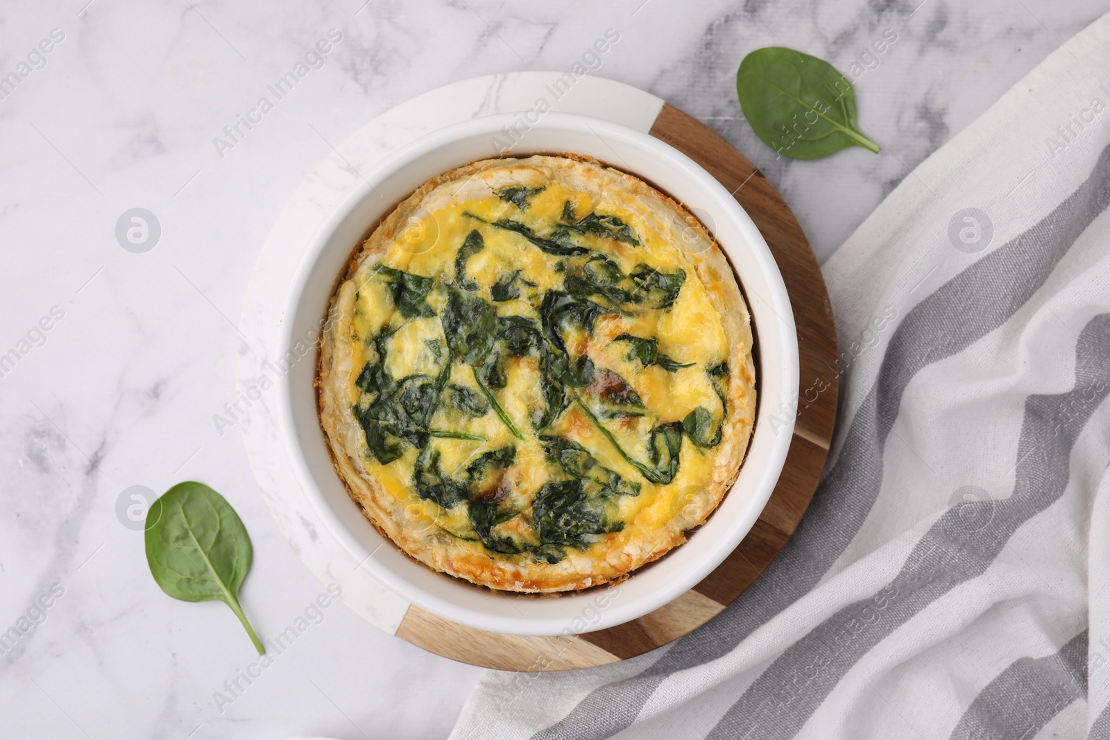 Photo of Delicious pie with spinach on white marble table, flat lay