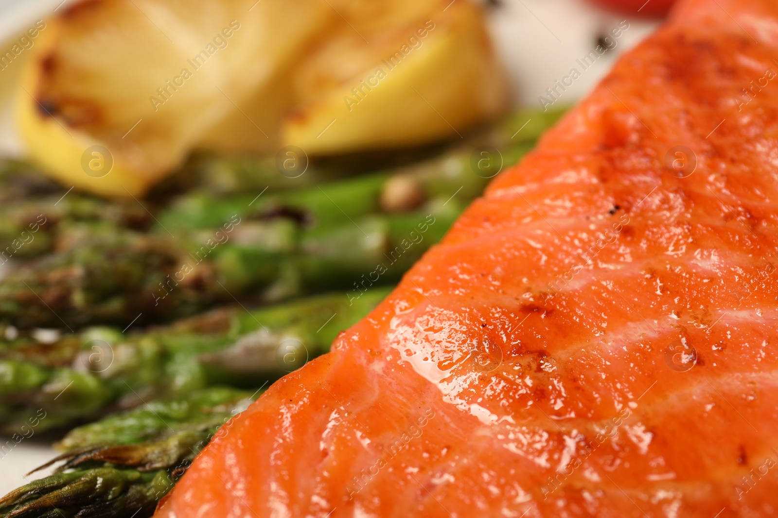 Photo of Tasty grilled salmon with asparagus on plate, closeup. Space for text