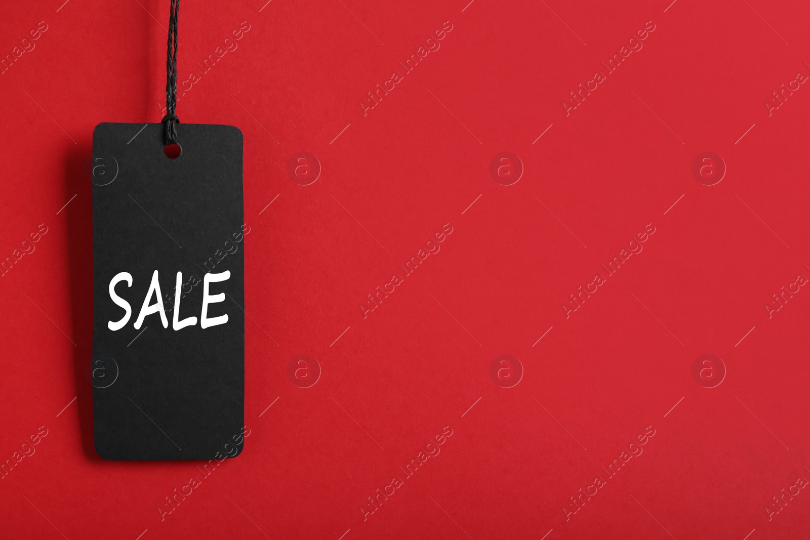 Photo of Sale tag on red background, space for text. Black Friday