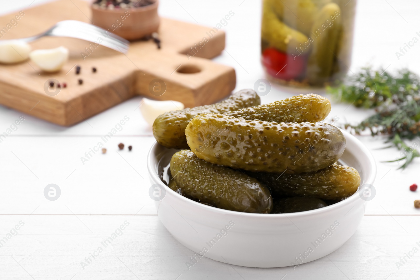 Photo of Tasty pickled cucumbers on white wooden table, space for text