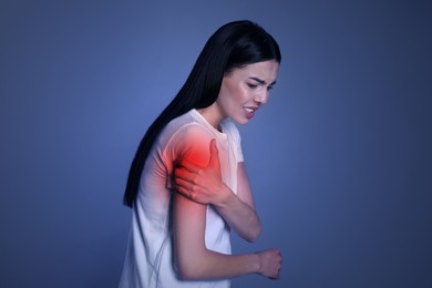 Woman suffering from shoulder pain on blue background