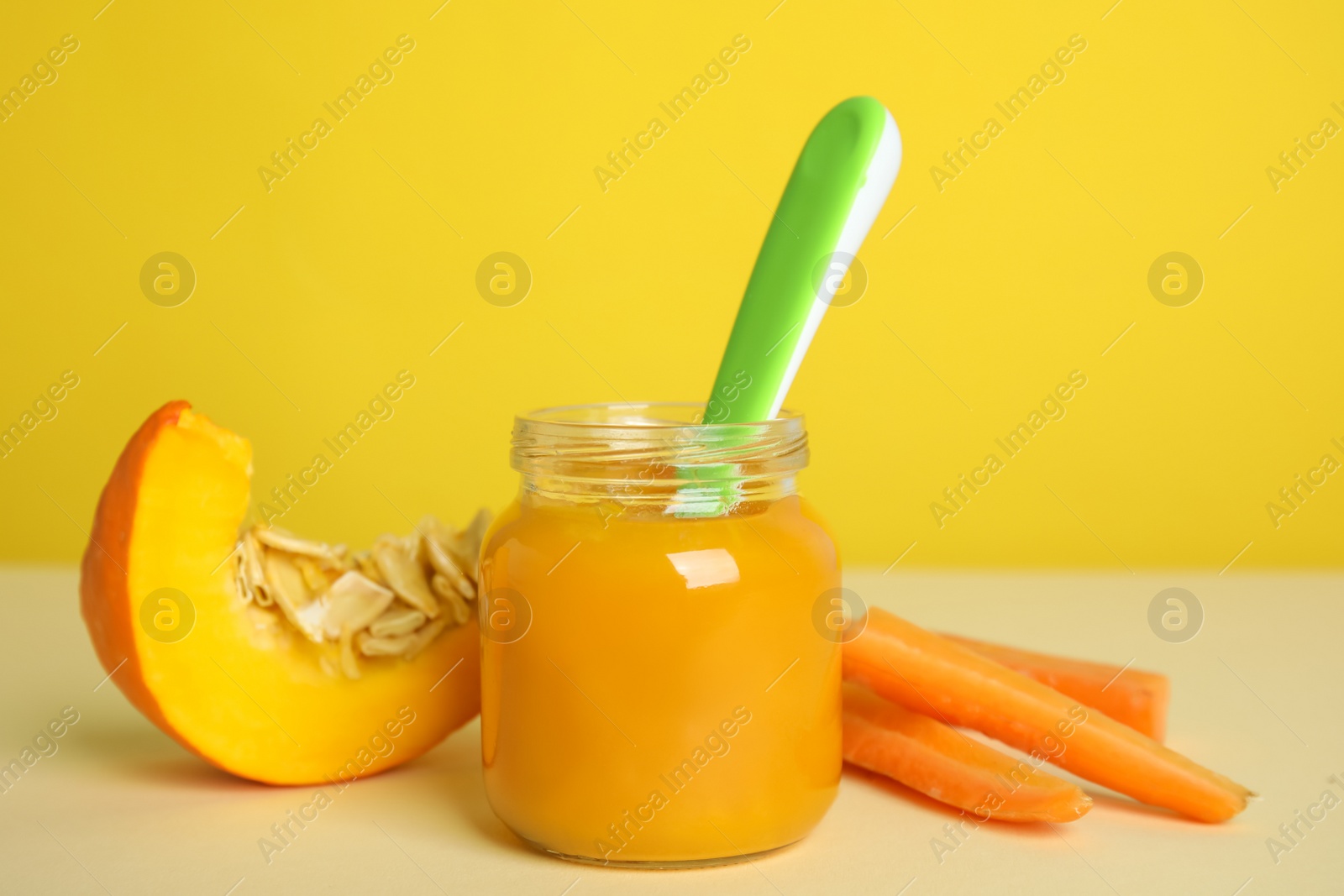 Photo of Healthy baby food and ingredients on table against yellow background