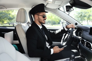 Photo of Young handsome driver in luxury car. Chauffeur service