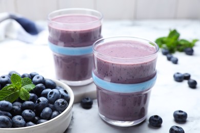 Photo of Tasty blueberry smoothie with mint and fresh berries on white marble table