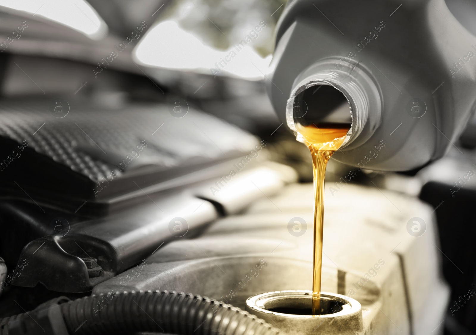 Image of Pouring motor oil into car engine, closeup. Color accent effect