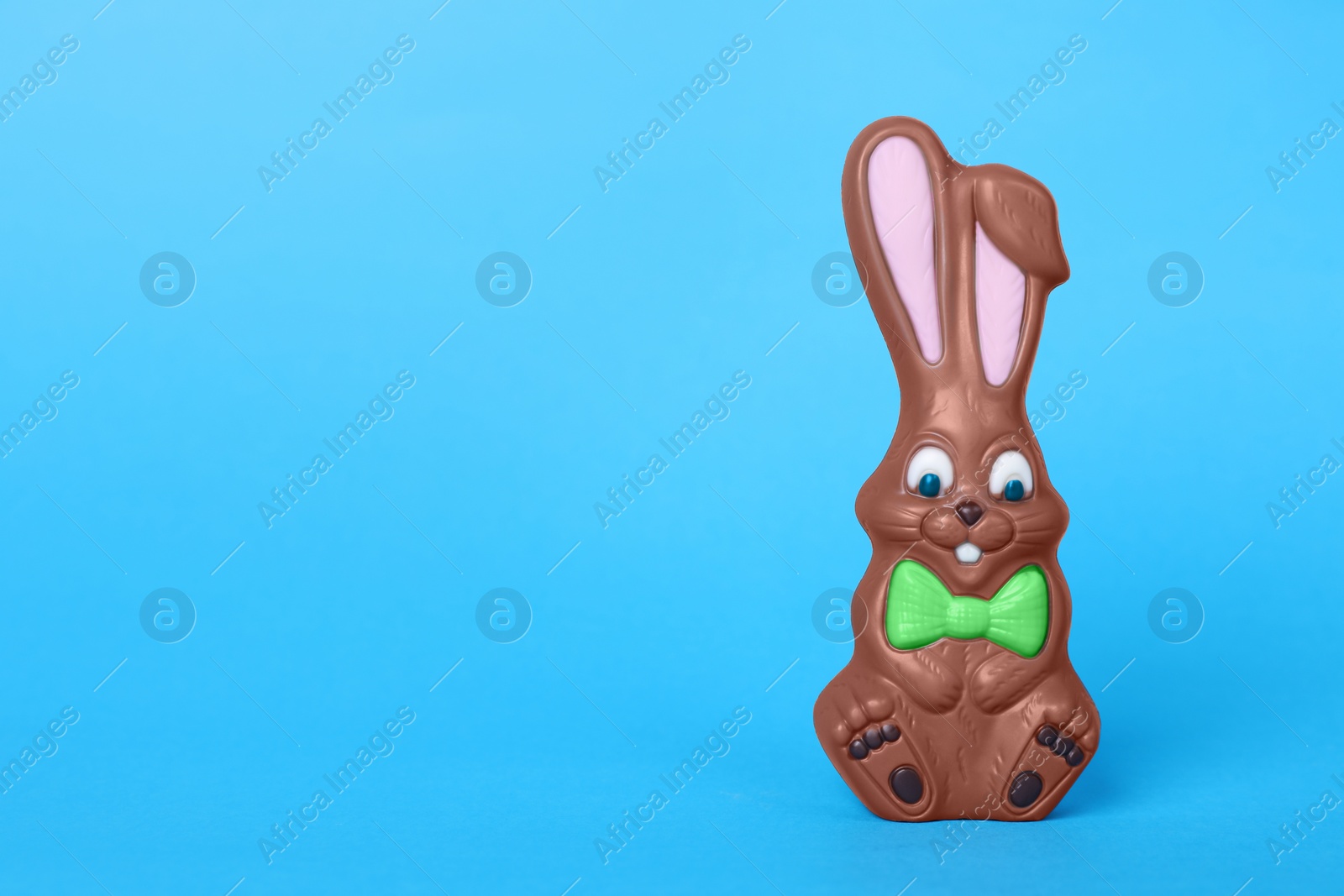 Photo of Chocolate bunny on light blue background, space for text. Easter celebration