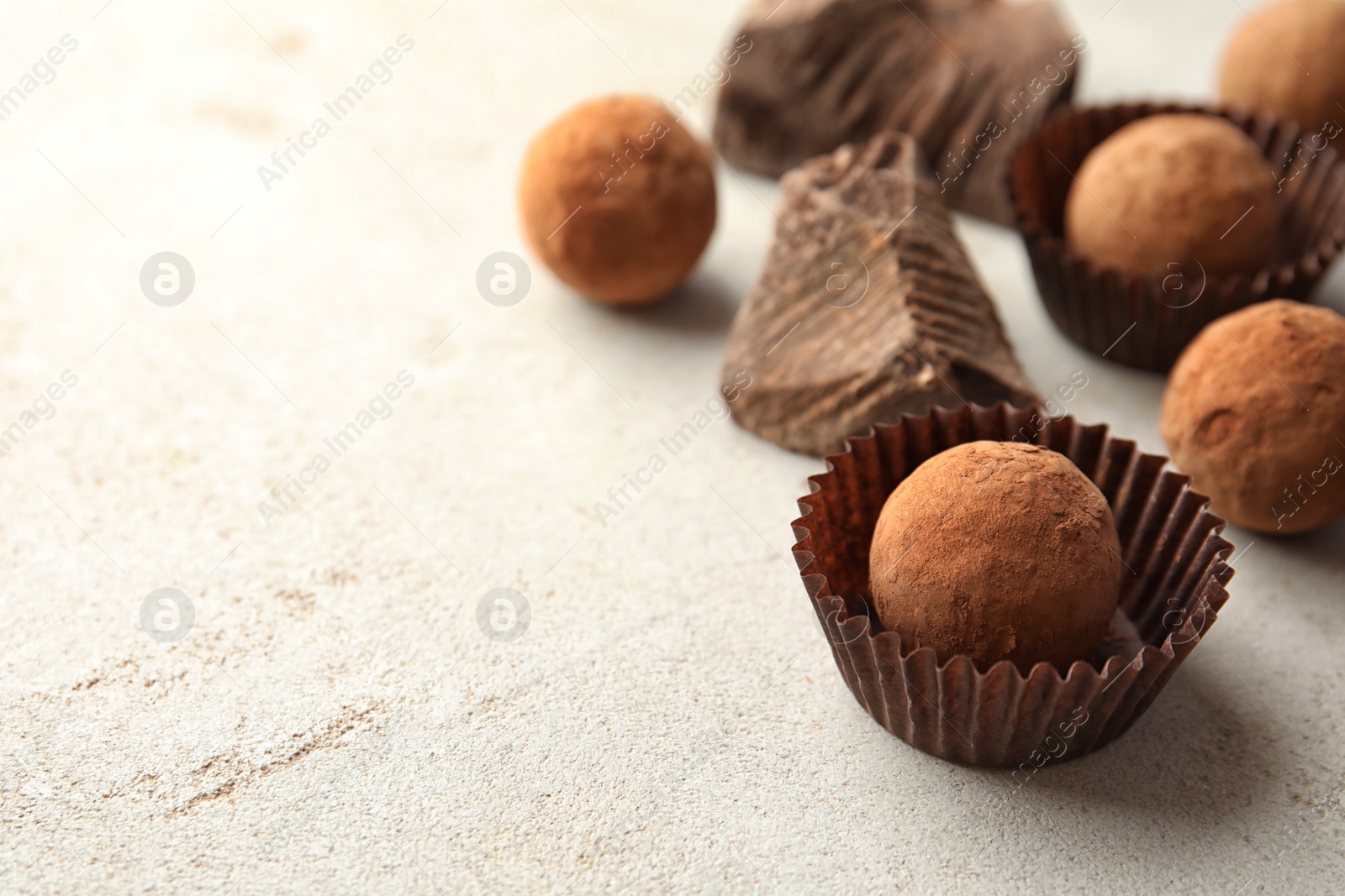 Photo of Tasty raw chocolate truffles on light background, space for text