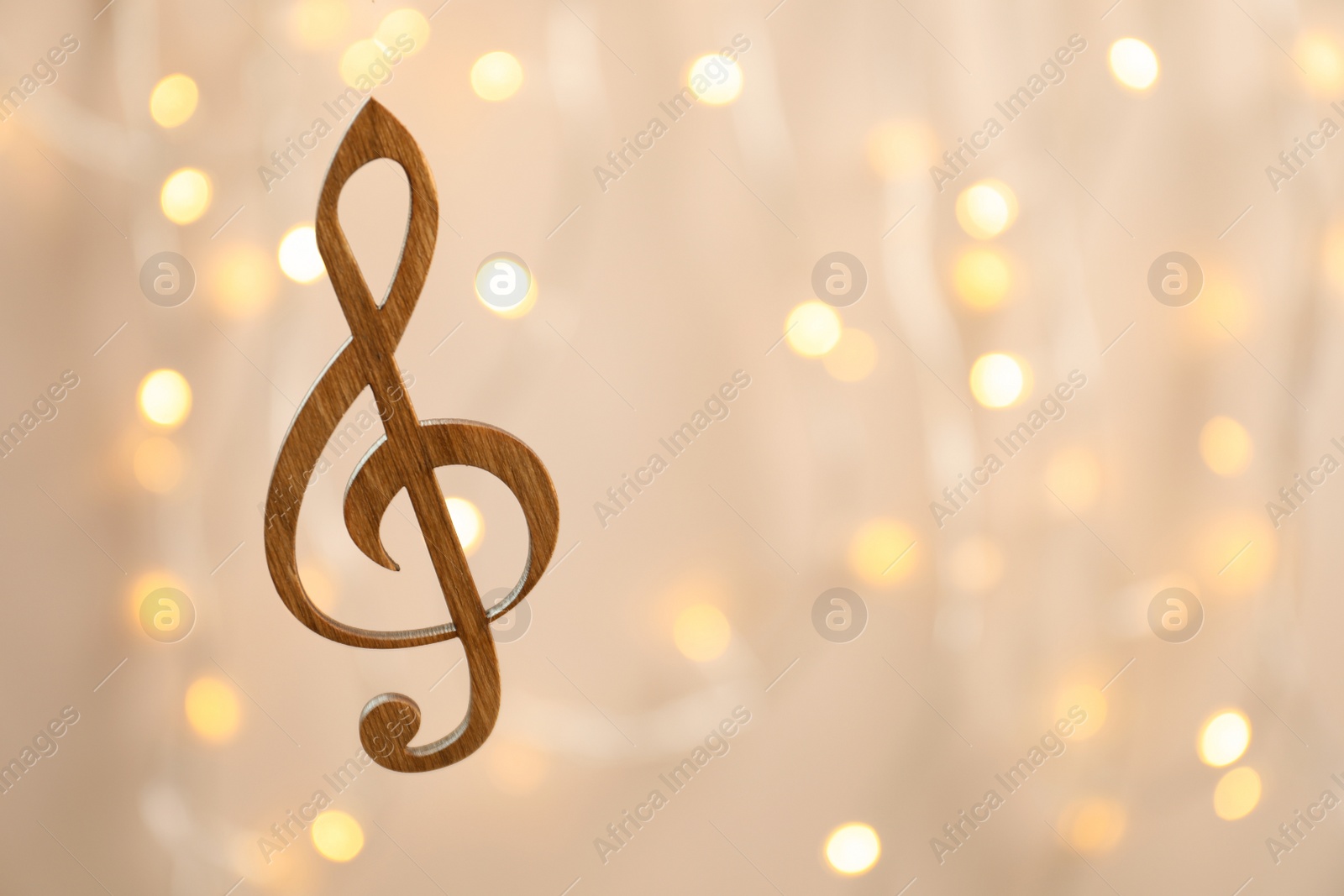 Photo of Wooden treble clef against blurred lights. Christmas music concept