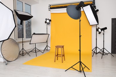Interior of modern photo studio with bar stool and professional lighting equipment