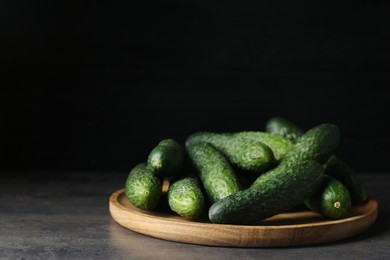 Photo of Wooden board with fresh ripe cucumbers on dark grey table, space for text