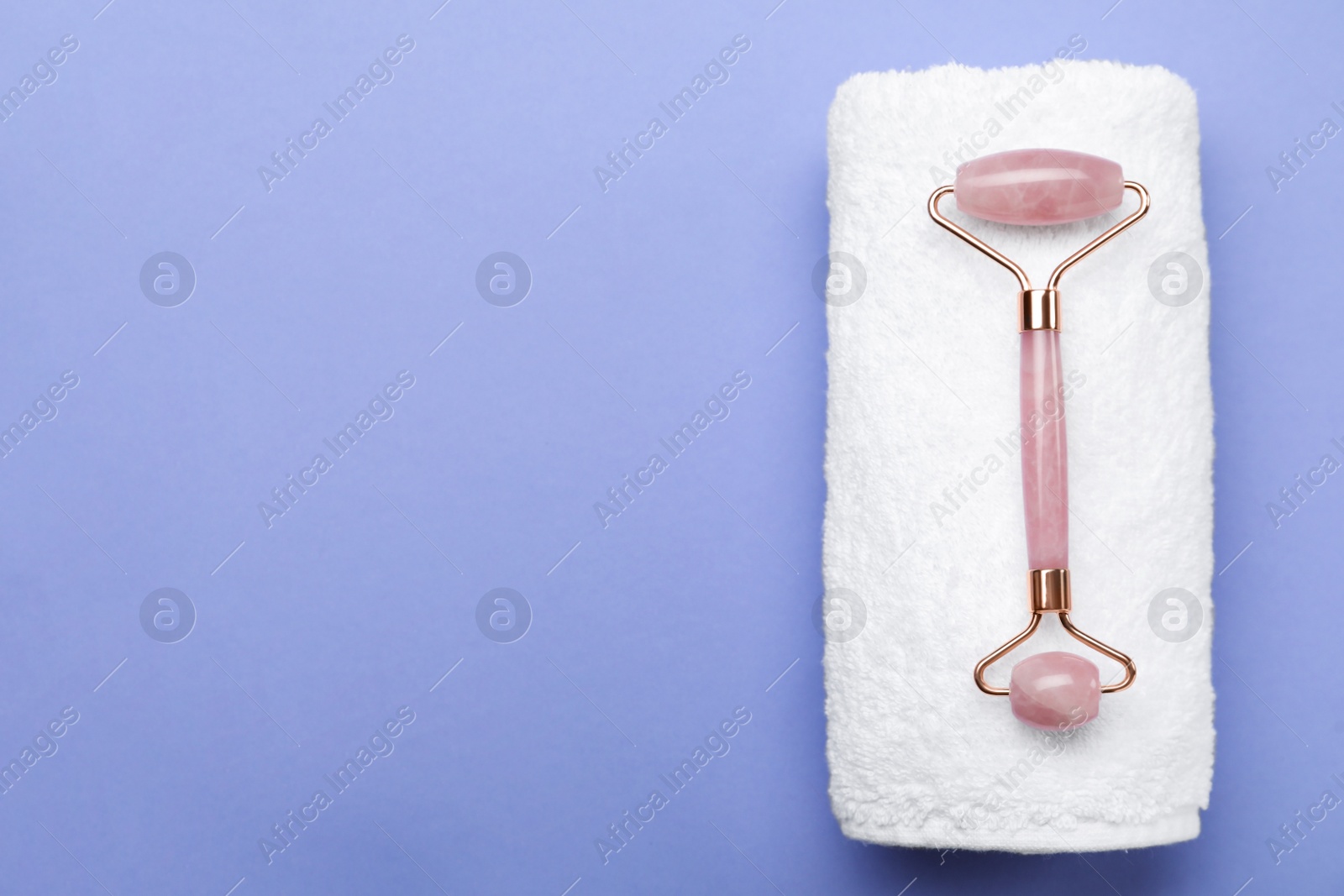 Photo of Natural face roller and towel on lilac background, top view. Space for text