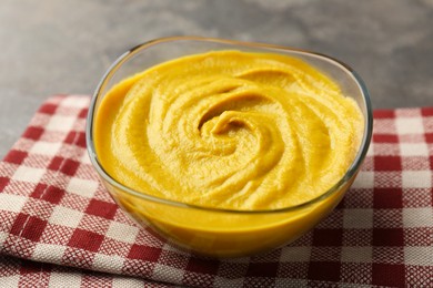 Photo of Tasty mustard sauce in glass bowl on grey table, closeup