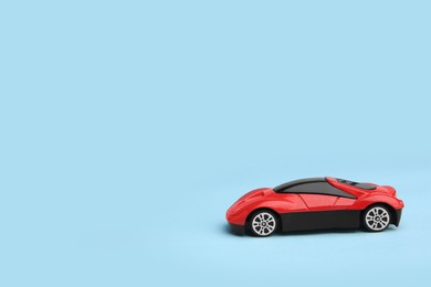 Photo of One red car on light blue background, space for text. Children`s toy
