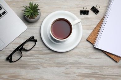 Photo of Ceramic mug of aromatic tea, laptop, glasses, houseplant and notebooks on white wooden table, flat lay