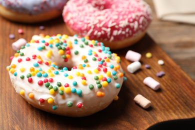 Yummy donut with sprinkles on board, closeup