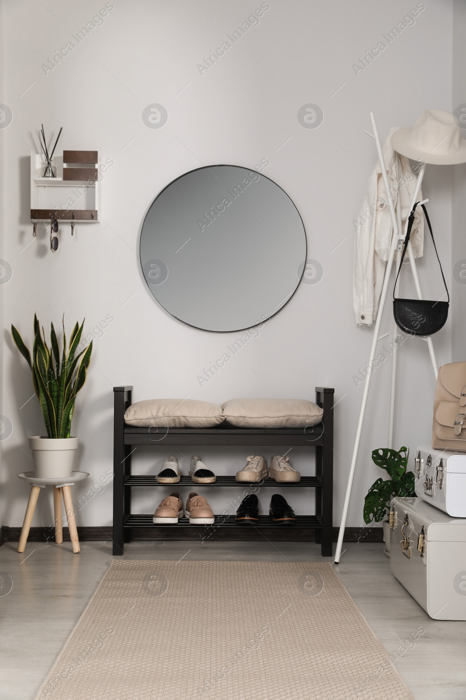 Photo of Hallway interior with stylish furniture and round mirror on light wall