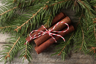 Photo of Cinnamon sticks and fir branches on wooden table, flat lay