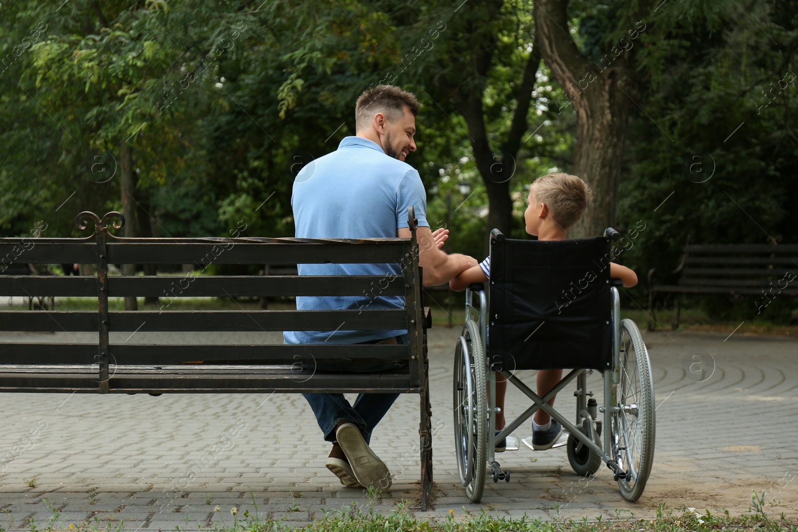 Photo of Father with his son in wheelchair at park