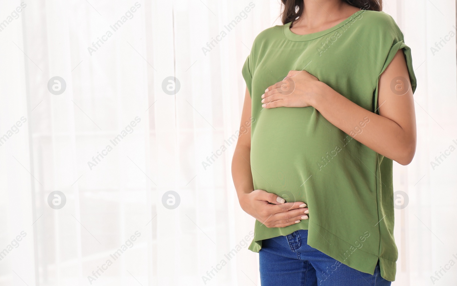 Photo of Beautiful pregnant woman near window at home