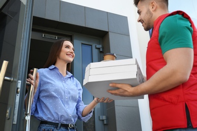 Courier giving order to young woman at open door. Food delivery service