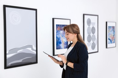 Photo of Beautiful young woman with tablet at exhibition in art gallery