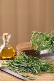 Fresh tarragon leaves and knife on wooden board, closeup