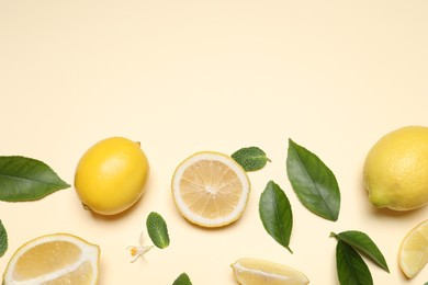 Photo of Many fresh ripe lemons with leaves and flower on beige background, flat lay. Space for text