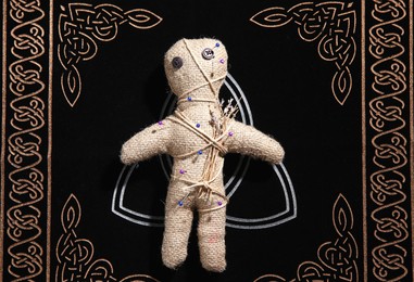 Photo of Voodoo doll pierced with pins on table, top view. Curse ceremony
