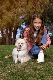 Little girl with her cute dog in park. Autumn walk