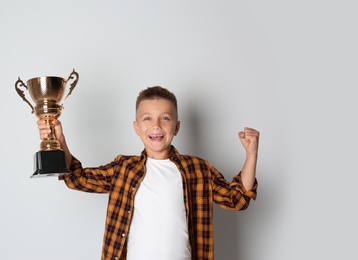 Photo of Happy boy with golden winning cup on white background
