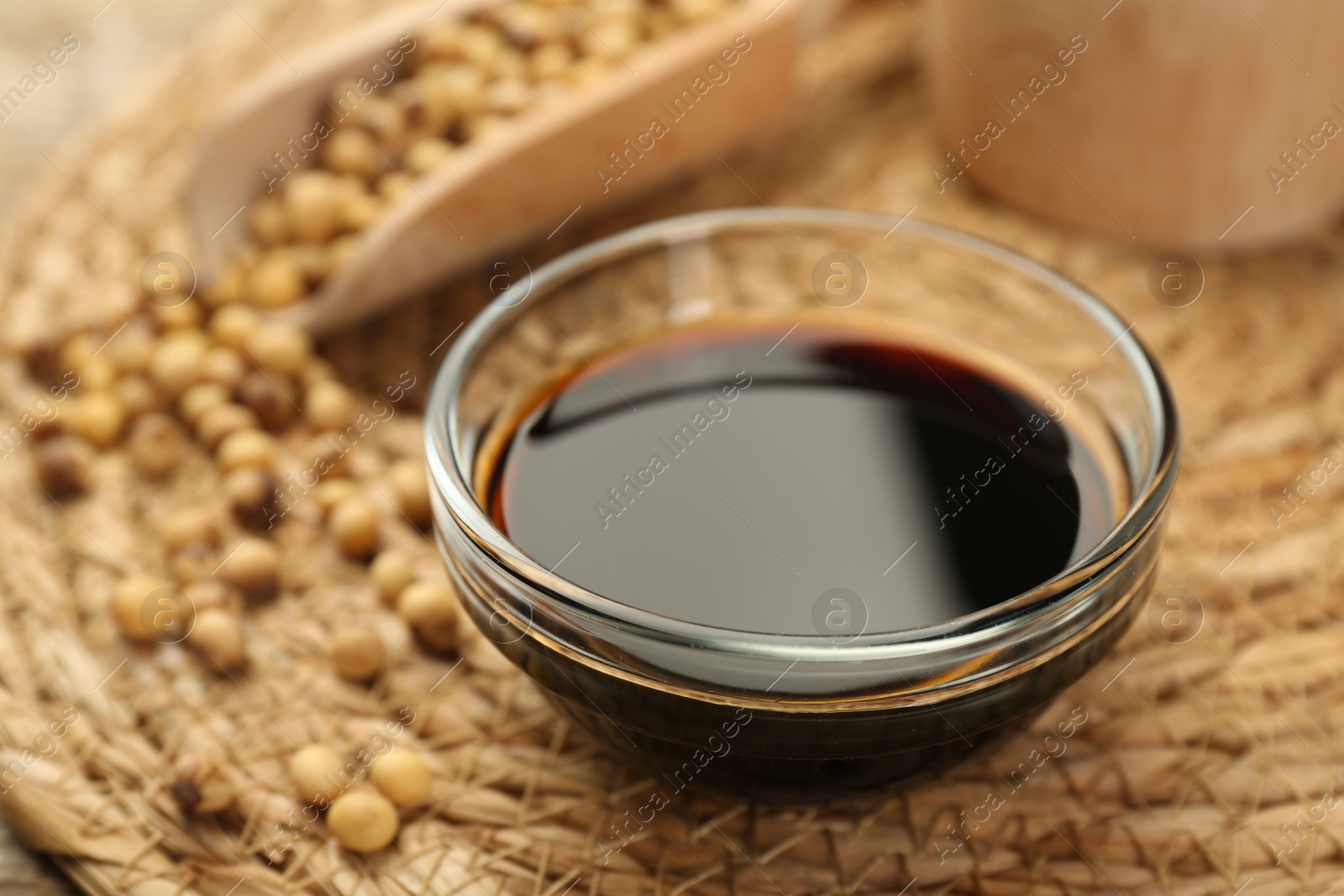 Photo of Soy sauce in bowl and beans on table, closeup