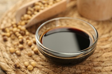 Photo of Soy sauce in bowl and beans on table, closeup