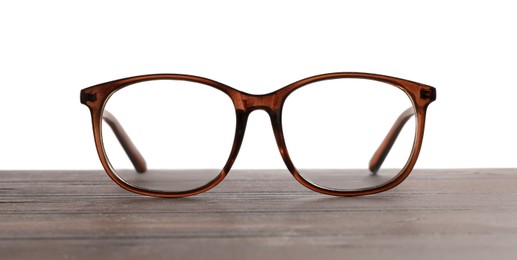 Stylish glasses with brown frame on wooden table against white background