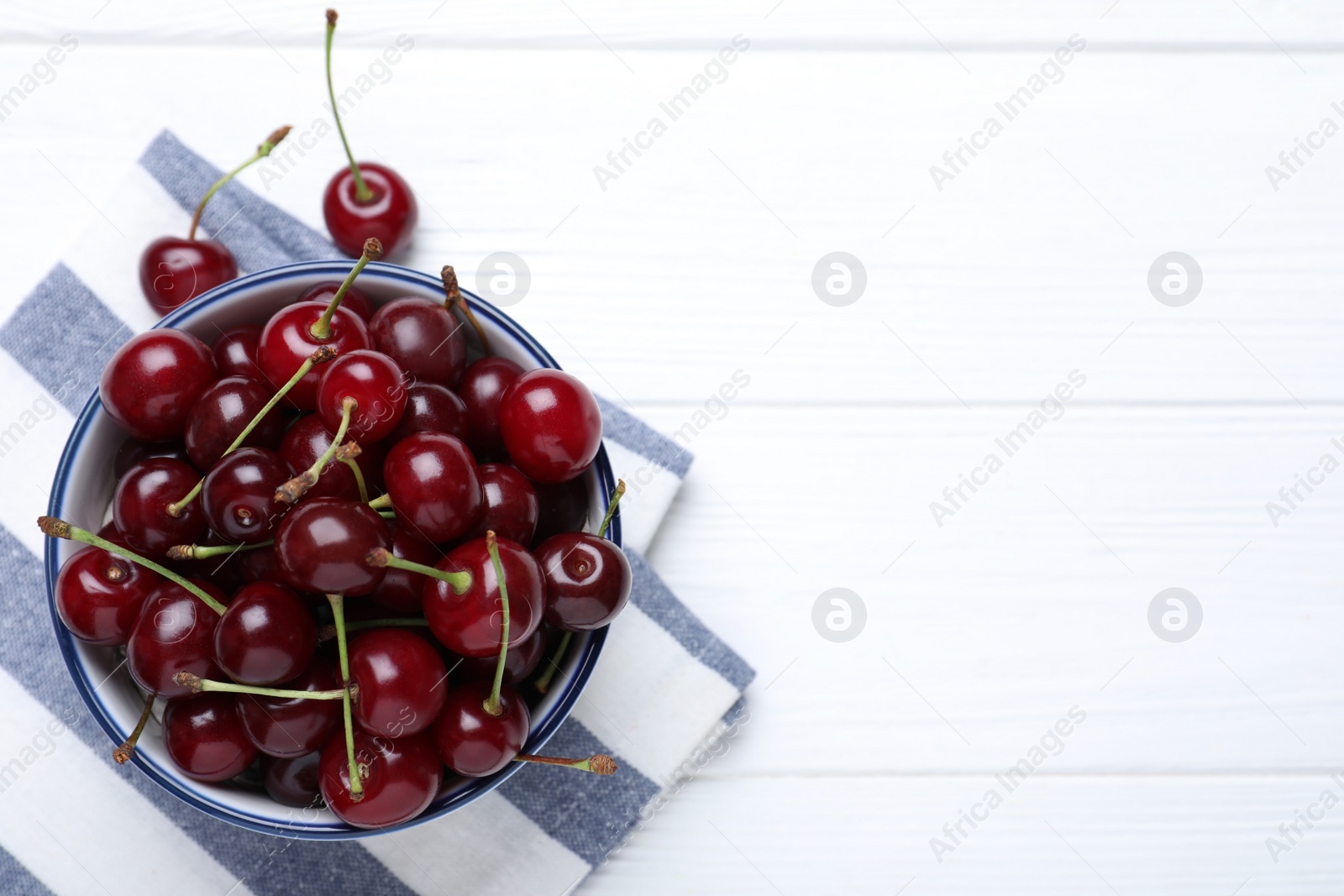 Photo of Sweet juicy cherries on white wooden table, top view. Space for text