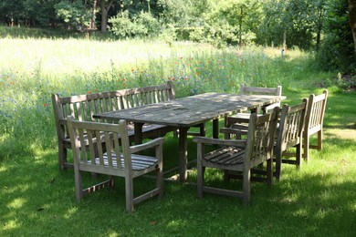 Empty wooden table with bench and chairs in garden