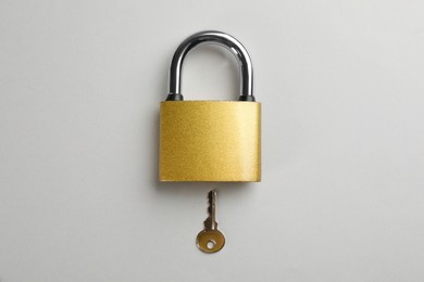 Photo of Modern padlock with key on light background, flat lay