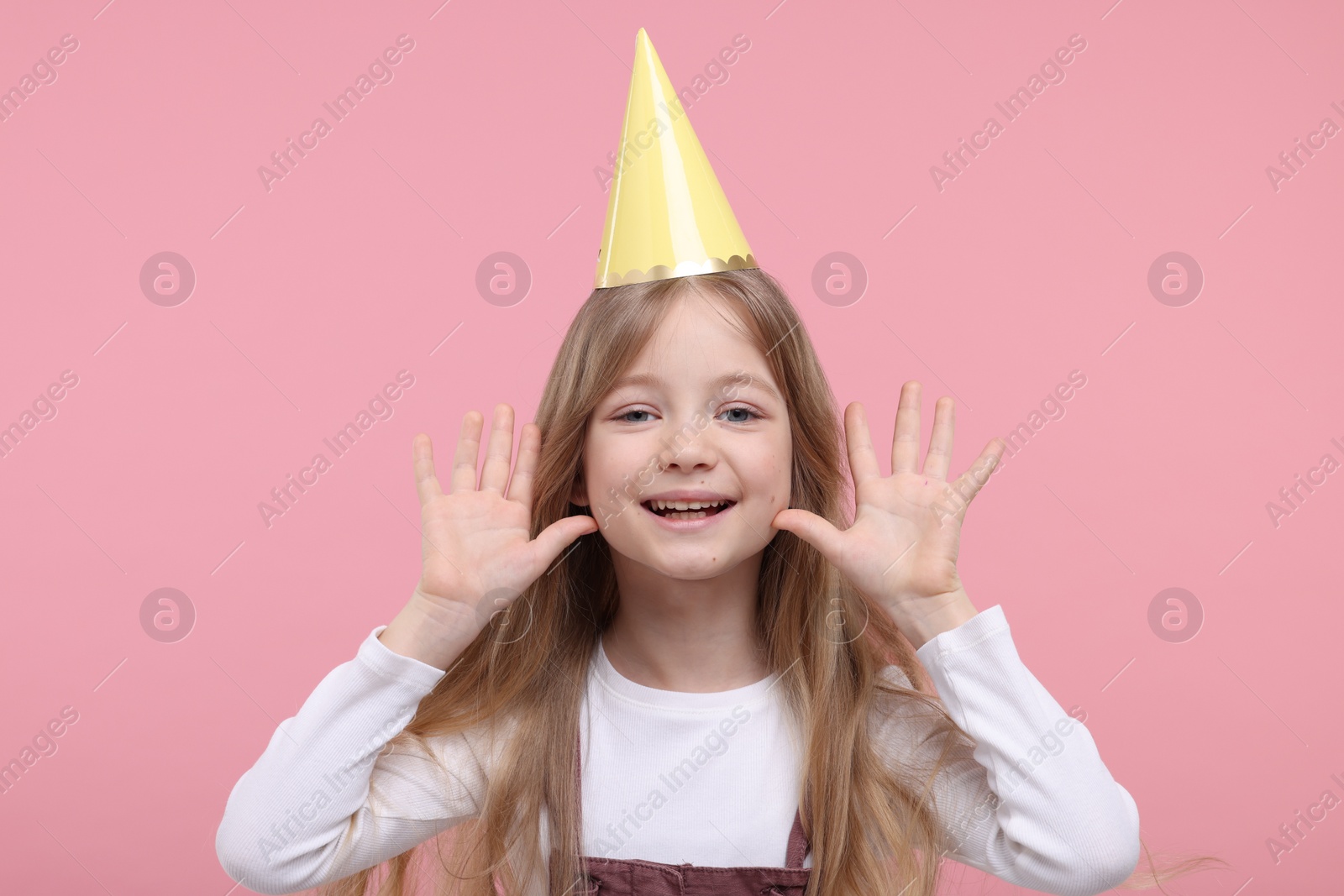 Photo of Happy little girl in party hat on pink background