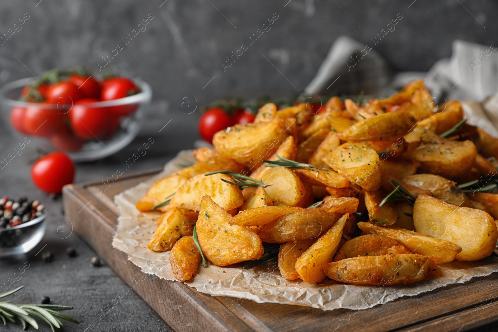 Photo of Wooden board with baked potatoes and rosemary on table