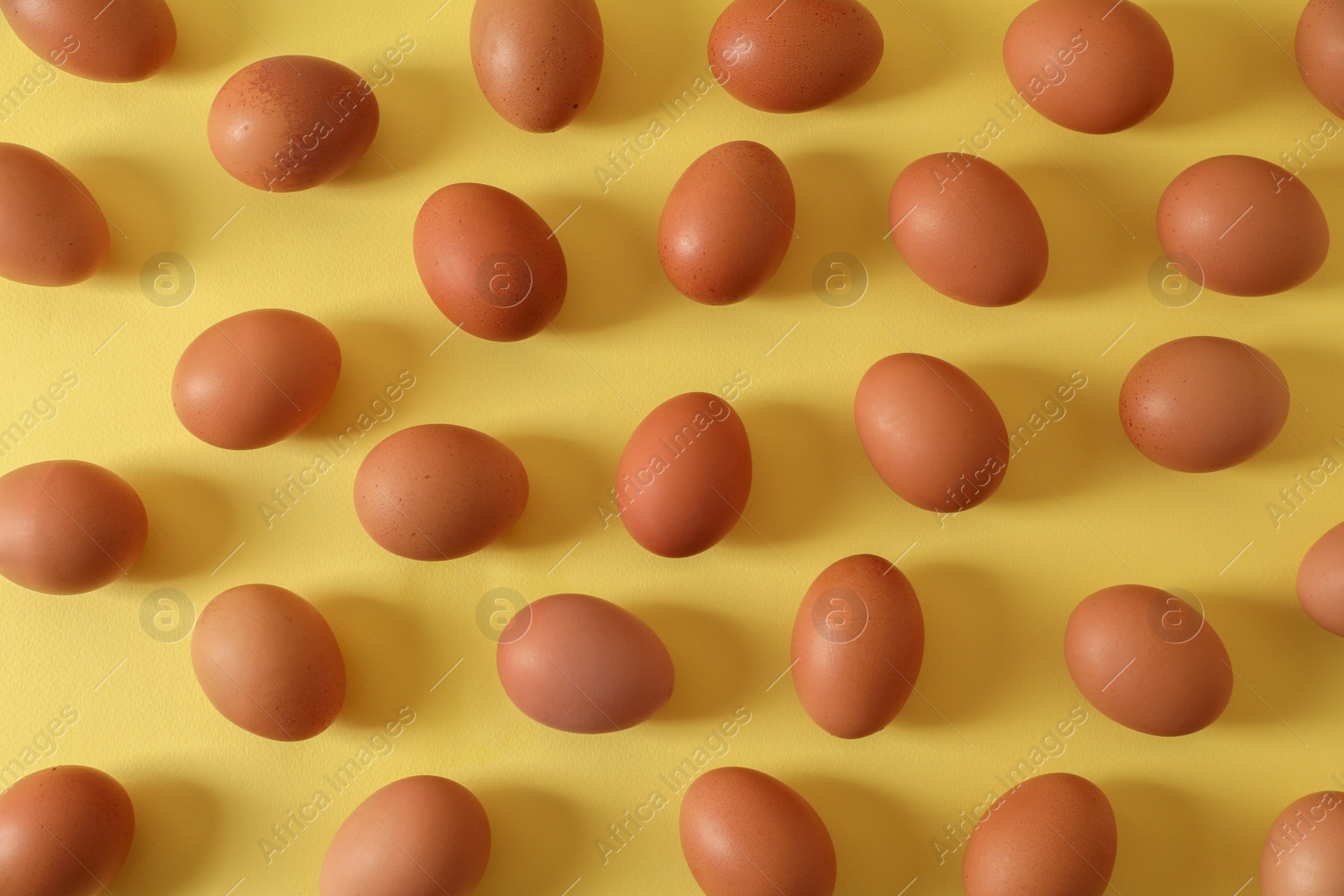 Photo of Fresh chicken eggs on yellow background, flat lay